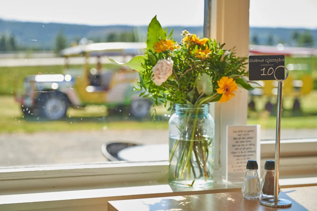 Blomster på et restaurantbord med utsikt mot grønt landskap