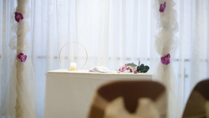 Lyst selskapslokale pyntet med blomster og hvite tekstiler